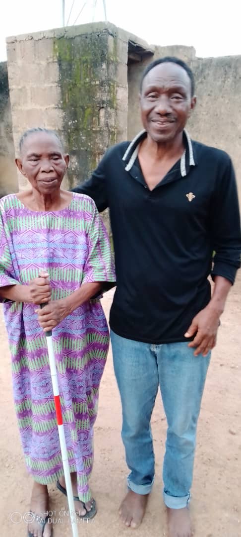 Vision X founder standing beside his grandmother, who is holding a white mobility cane.